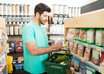 smiling young man checking shopping list supermarket